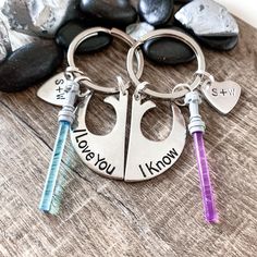 two personalized key chains with names on them sitting next to some rocks and stones