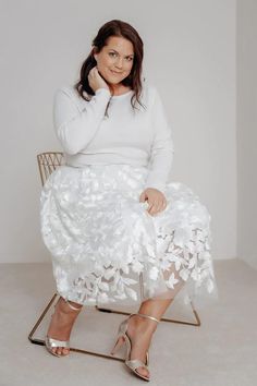 a woman sitting on top of a chair in a white dress