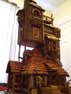 a house made out of clay sitting on top of a floor next to a window