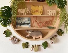 a wooden shelf filled with stuffed animals and greenery on top of a white wall