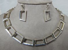 "Here's a wonderful vintage sterling silver parure by noted Taxco artisan, Juan Sandoval Vazquez, with a contemporary design. Pieces feature trapezoid shapes in an open link construction. The choker style necklace is 15\", and the bracelet is 7\" long. All the links are just over 1/2\" wide. The earrings have a dangle style with button and post tops. Necklace and bracelet are marked, '925 TS-30 MEXICO' and have the Two Trees logo mark, on the backs of the hidden box clasp. Substantial (total wei Modern Formal Jewelry Stamped 925, Contemporary Hallmarked Jewelry As Gift, Contemporary Rectangular Jewelry With Polished Finish, Contemporary Formal Jewelry With Rectangular Shape, Contemporary Silver Jewelry For Anniversary, Contemporary Jewelry With Matching Earrings For Formal Events, Contemporary Rectangular Jewelry For Formal Occasions, Contemporary Formal Rectangular Jewelry, Modernist Stamped 925 Jewelry For Formal Occasions