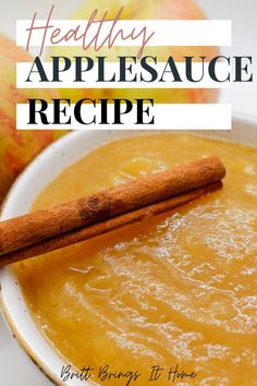 a white bowl filled with applesauce next to an apple and cinnamon stick on top