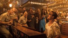 a man standing in front of a bar with lots of people around him and his mouth open