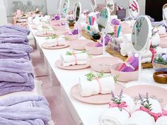 there are many towels and soaps on the table with pink plates in front of them