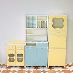 an assortment of kitchen furniture in pastel colors on a tiled floor with white walls