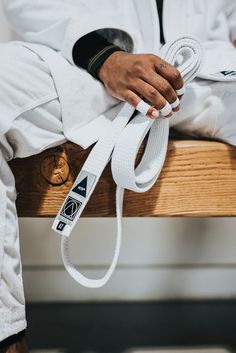 a man sitting on top of a wooden bench holding onto a white belt with two hands