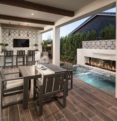 a dining room table with chairs and a fire place in the back ground near a swimming pool