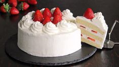 a cake with white frosting and fresh strawberries on top is cut in half