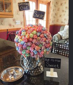 a vase filled with lots of colorful candies on top of a table next to a sign