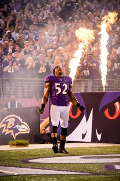 a football player standing on the field with his arms in the air and fire coming out of his mouth