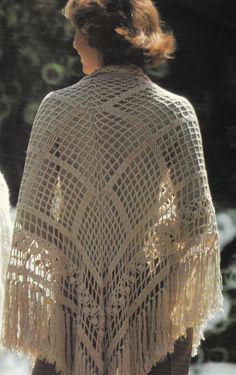 a woman wearing a crocheted shawl with fringes on her shoulders and back