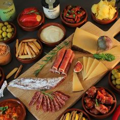 a table topped with lots of different types of cheeses and meats on top of wooden cutting boards