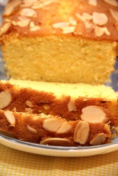 a loaf of lemon almond bread on a plate with a slice cut out and ready to be eaten