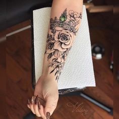 a woman's arm with flowers and a crown tattoo on her left hand,