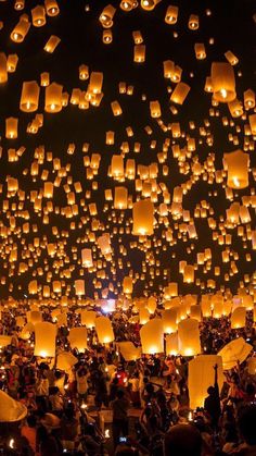 many people are flying lanterns in the sky at night time with lights on them and candles lit up