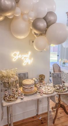 a table topped with lots of desserts and balloons hanging from the ceiling above it