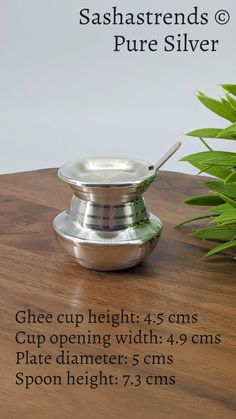 a silver plate sitting on top of a wooden table next to a potted plant