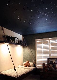 a room with a bed, window and night sky painted on the ceiling above it