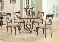 a dining room table with four chairs and a rug on the floor in front of it