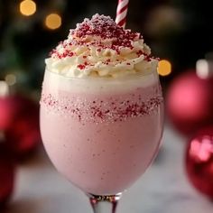 a pink drink with white and red sprinkles on it's rim