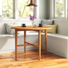 a wooden table with two cups on it next to a bench and window sill