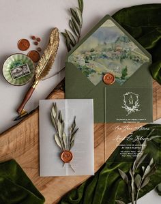 the wedding stationery is laid out on top of green leafy paper and gold foil