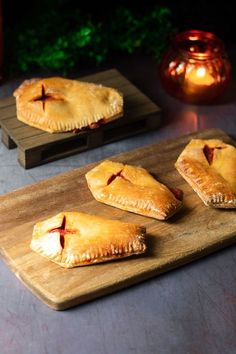 three pastries on a wooden cutting board next to candles