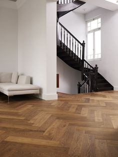 a white couch sitting in front of a stair case on top of a hard wood floor