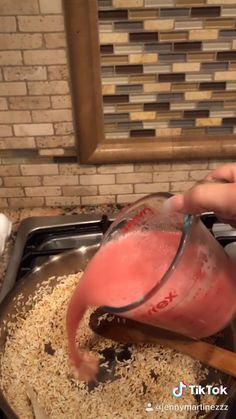 a person pouring something into a pan filled with food