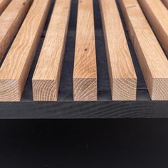 a close up of a wooden bench with black slats on the top and bottom