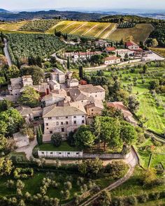 an aerial view of a village surrounded by green fields and olive trees in the countryside