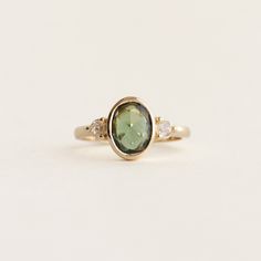 a ring with a green stone and two white diamonds