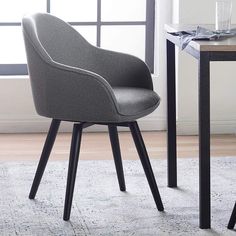 a gray chair sitting on top of a rug next to a table