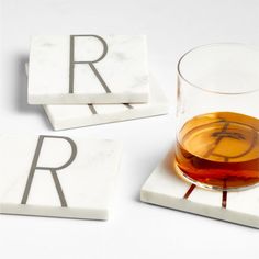 marble coasters with the letter r on them and a glass of liquid in front