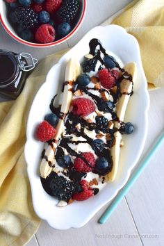 a white plate topped with bananas and berries next to a bowl of chocolate ice cream