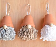 three different types of mop holders on a wooden surface with white and gray pom - poms