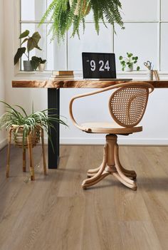 a wooden table with a laptop on it next to a potted plant and chair