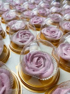 many cupcakes with pink frosting on them are displayed in glass dishes and gold rimmed trays