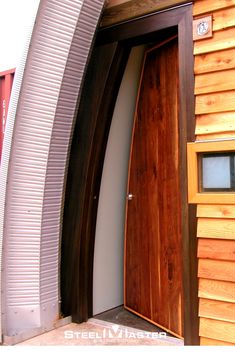 a wooden door is open on the side of a building that has curved metal and wood doors