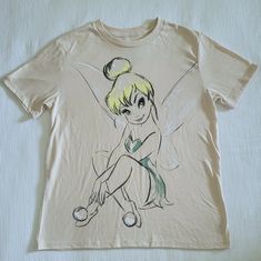 Brand New Without Tags (Swift Tack Still Attached) Disney Tinkerbell Graphic Tee Excellent Condition With No Flaws Size Small (Fits More Like A Medium, See All Measurements) Approx Measurements Laying Flat: Length 24" Armpit To Armpit 19.5" Across Bottom Hem 20.5" 50% Cotton 50% Polyester Color Of Tee Is A Light Wheat With A Sketch Of Tinkerbell On The Front Crew Neckline, Short Sleeves, Straight Hem Please No Trades Or Lowballs! *Ask Any Questions You May Have Prior To Making An Offer* Tinkerbell Tattoo, Tinkerbell Shirt, Disney Tinkerbell, Disney Tops, Crew Neckline, Wheat, Graphic Tee, Swift, Graphic Tees