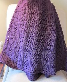 a purple crocheted blanket sitting on top of a white chair