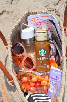 a basket filled with food and drinks on top of a beach