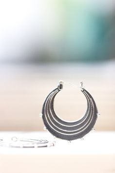 "Evocative of raindrops striking a pool of water, circles radiating outward from the point of impact and smaller droplets becoming airborne. These earrings are made completely of sterling silver, right down to the ear wires which are hinged and connect in a catch on the other side. The line and ball design is repeated on both sides of each earring. Each hoop measures approximately 1.25\" in diameter. The hoops have been given a patina to darken them and then tumbled in steel shot to give them a Modern Nickel-free Drop Hoop Earrings, Everyday Metal Drop Hoop Earrings, Unique Teardrop Hoop Earrings For Everyday, Metal Drop Hoop Earrings With Ear Wire, Nickel-free Metal Drop Hoop Earrings, Round Teardrop Earrings For Everyday, Unique Dangle Hoop Earrings For Everyday, Everyday Round Teardrop Pierced Earrings, Everyday Drop Hoop Earrings