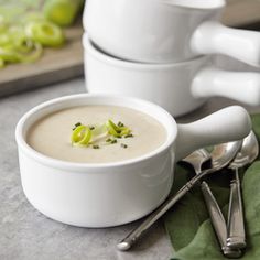 there is a bowl of soup and two spoons on the table next to it