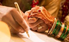 the bride and groom are signing their wedding vows at the ceremony table with gold bracelets on each hand