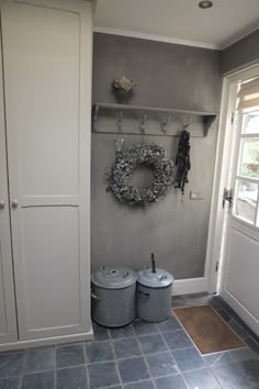 two buckets are sitting in front of a door with a wreath on the wall