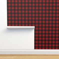 a red and black plaid wallpaper next to a white door with a wooden floor