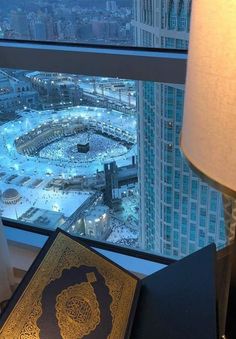 an open book sitting on top of a table next to a lamp and a window