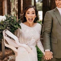 the bride and groom are holding hands while walking through the woods with flowers in their hand