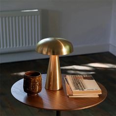 a table with a lamp, book and cup on it in the middle of a room